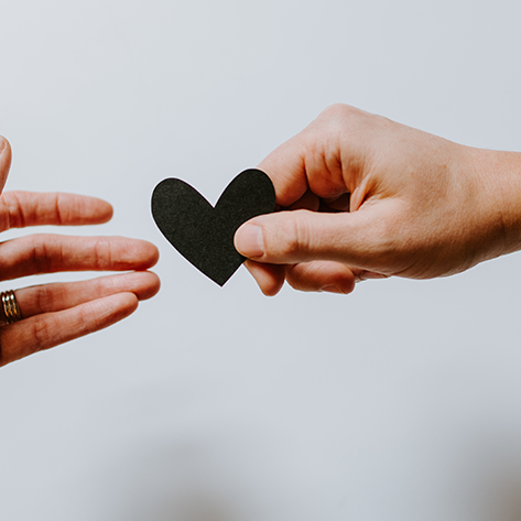 6 – One hand handing a black paper heart to other hand – unsplash
